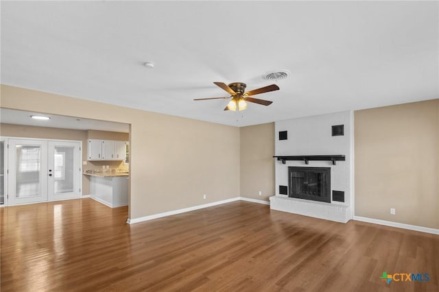 454 W Ward St, Goliad, TX 77963 - unfurnished living room with a ceiling fan, wood finished floors, and a brick fireplace