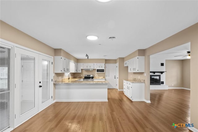 454 W Ward St, Goliad, TX 77963 - kitchen featuring a peninsula, stainless steel electric range, light wood-style flooring, white microwave, and white cabinets
