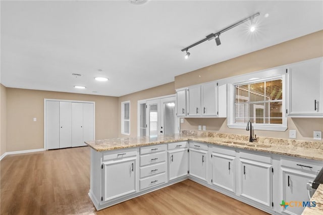 454 W Ward St, Goliad, TX 77963 - kitchen with a peninsula, white cabinetry, light wood-type flooring, and light stone countertops