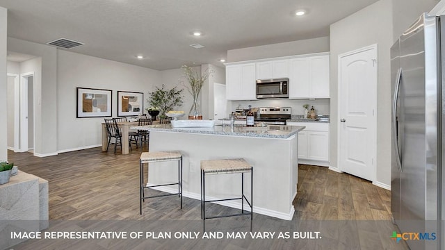 1000 Village Run, Seguin, TX 78155 - kitchen with stainless steel appliances, dark wood-style flooring, a kitchen breakfast bar, light stone counters, and white cabinetry