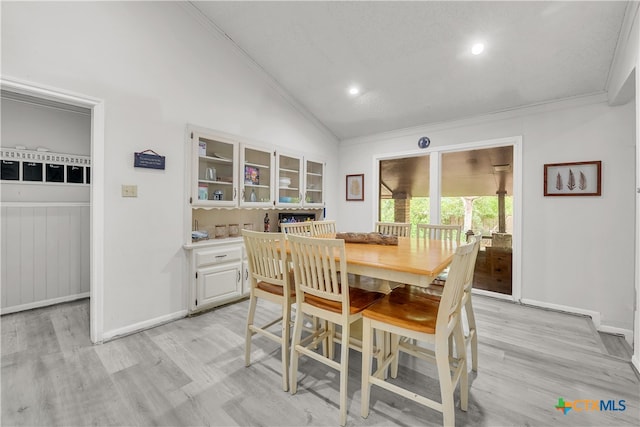 dining space featuring light wood-type flooring, vaulted ceiling, and ornamental molding