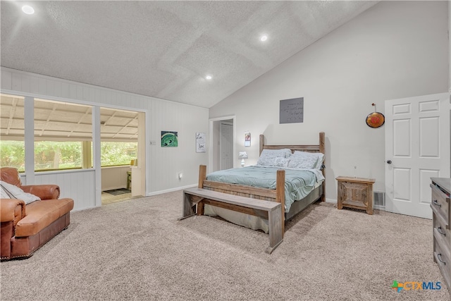 carpeted bedroom with wood walls, a textured ceiling, and high vaulted ceiling