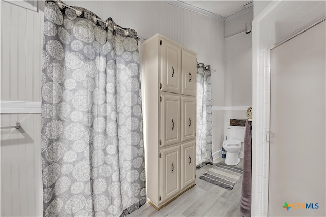 bathroom featuring toilet, hardwood / wood-style floors, and ornamental molding