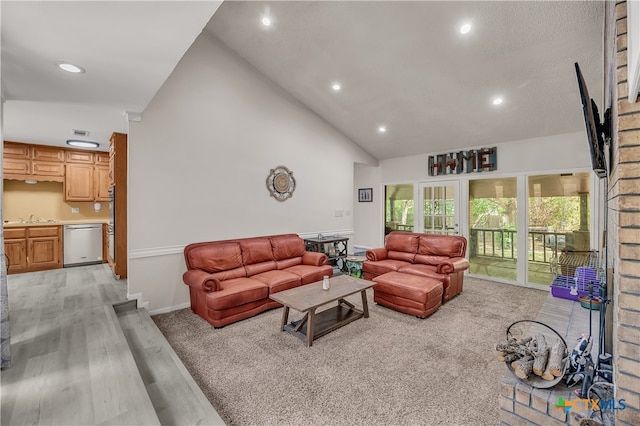 living room featuring high vaulted ceiling, light wood-type flooring, and sink