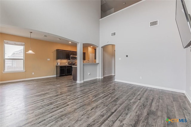 1233 Jester Ct, Copperas Cove, TX 76522 - unfurnished living room featuring arched walkways, baseboards, dark wood-style flooring, and visible vents