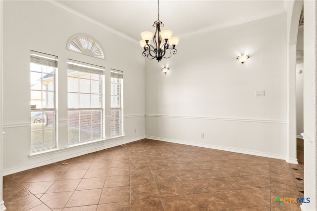 tiled empty room featuring baseboards, a notable chandelier, and crown molding