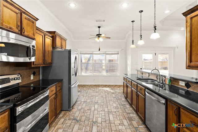 kitchen featuring ceiling fan, ornamental molding, a sink, appliances with stainless steel finishes, and tasteful backsplash