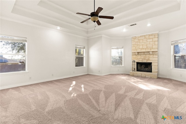 unfurnished living room with a tray ceiling, carpet, visible vents, and ornamental molding