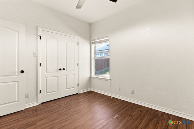 unfurnished bedroom featuring dark wood finished floors, a closet, baseboards, and a ceiling fan