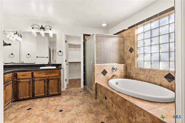 full bathroom featuring a walk in closet, a stall shower, vanity, and a bath