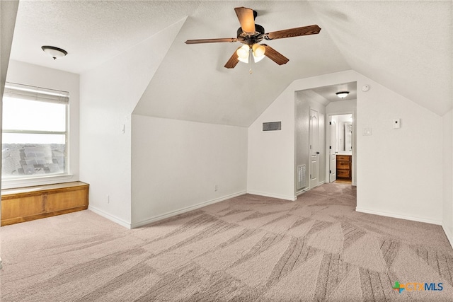 additional living space featuring lofted ceiling, carpet, visible vents, and a textured ceiling