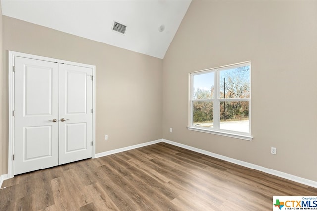 unfurnished bedroom featuring a closet, lofted ceiling, and hardwood / wood-style flooring