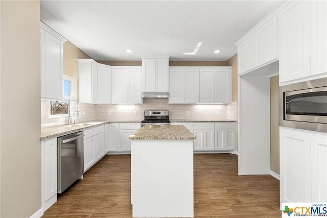 kitchen featuring white cabinets, appliances with stainless steel finishes, a center island, and sink