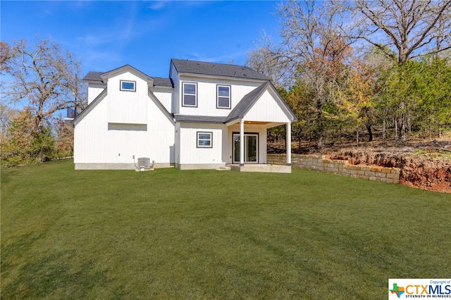 rear view of property with central AC unit and a lawn