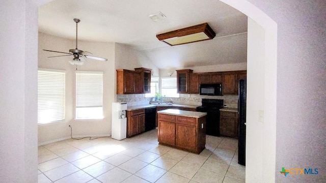 kitchen with lofted ceiling, black appliances, light tile patterned floors, ceiling fan, and a kitchen island