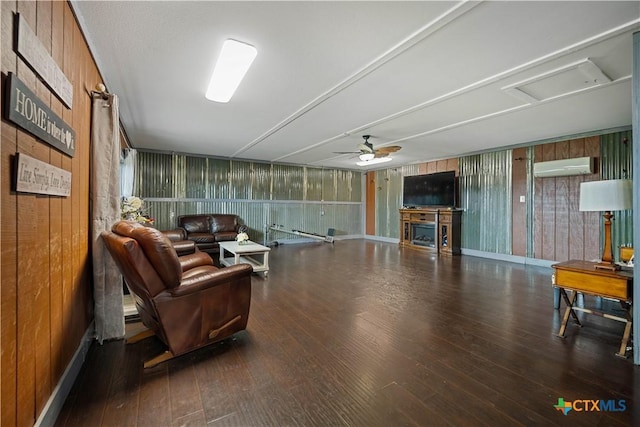 living room featuring wood-type flooring, a ceiling fan, a wall unit AC, and wood walls