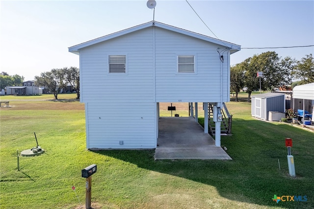 back of house with a storage unit and a yard