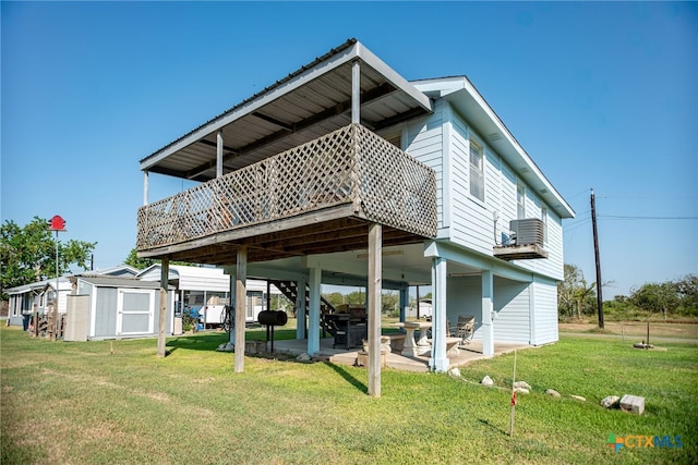 rear view of house featuring a deck, central AC, a storage shed, a lawn, and a patio area