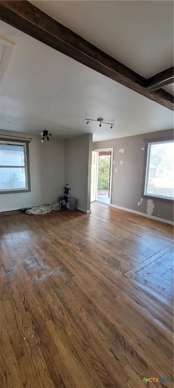 unfurnished living room with beam ceiling, hardwood / wood-style flooring, and a healthy amount of sunlight