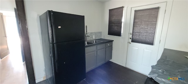 kitchen with dark hardwood / wood-style floors, black fridge, and sink