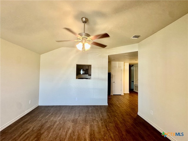 empty room with dark hardwood / wood-style flooring, vaulted ceiling, ceiling fan, and a textured ceiling