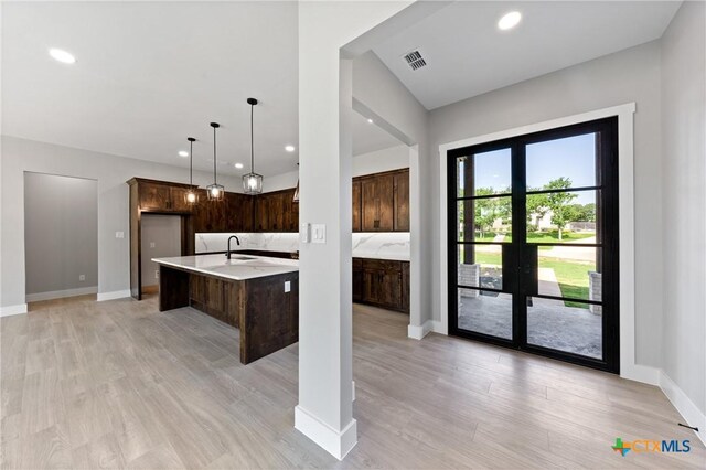 644 Creekside Dr, Belton, TX 76513 - kitchen with light countertops, dark brown cabinetry, a center island with sink, recessed lighting, and light wood-style floors