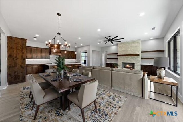 644 Creekside Dr, Belton, TX 76513 - dining space with light wood finished floors, a chandelier, a fireplace, a ceiling fan, and recessed lighting