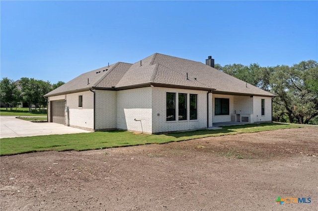 644 Creekside Dr, Belton, TX 76513 - rear view of house with driveway, brick siding, an attached garage, a chimney, and roof with shingles