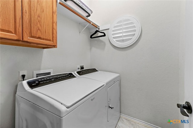 laundry area with cabinet space, washer and clothes dryer, and marble finish floors