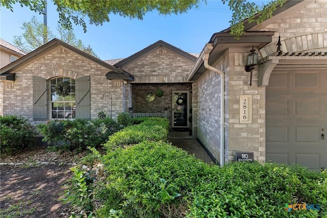 view of front of property with an attached garage, brick siding, and stone siding