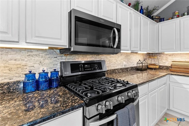 kitchen featuring stainless steel appliances, white cabinets, light tile patterned flooring, decorative backsplash, and dark stone counters