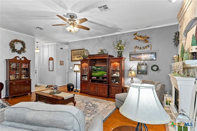 living room featuring ornamental molding, ceiling fan, and light wood-type flooring