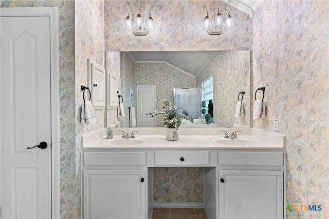 bathroom with wallpapered walls, ornamental molding, lofted ceiling, double vanity, and tile patterned floors
