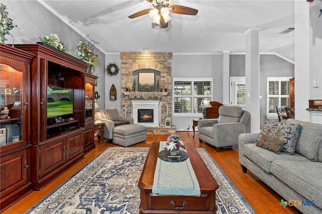 living room featuring crown molding, a large fireplace, ceiling fan, and light wood-type flooring