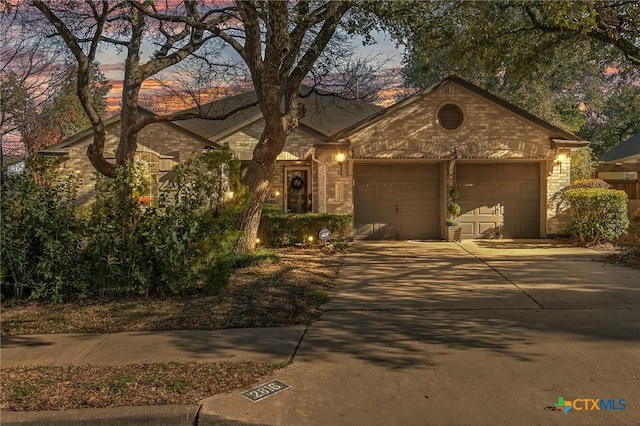 view of front of home featuring an attached garage, driveway, and brick siding