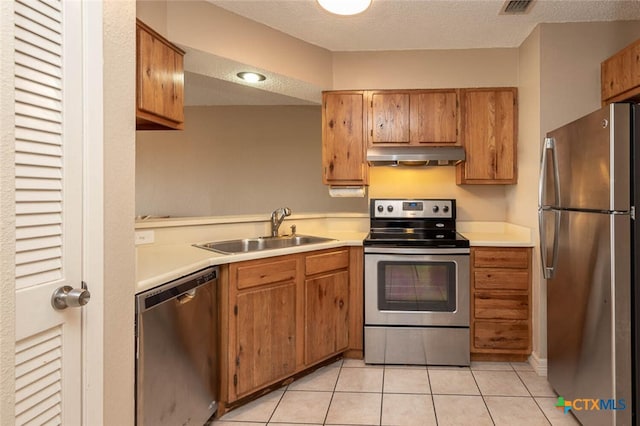 kitchen with light tile patterned flooring, a textured ceiling, sink, and appliances with stainless steel finishes