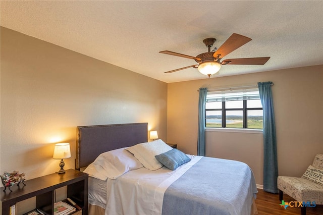 bedroom with hardwood / wood-style floors, ceiling fan, and a textured ceiling