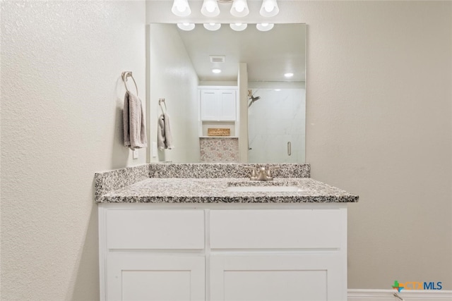 bathroom featuring walk in shower and vanity