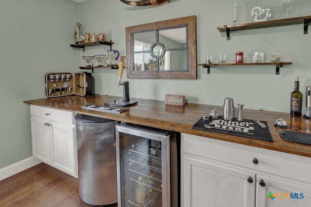 bar with wine cooler, wood finished floors, a dry bar, and baseboards