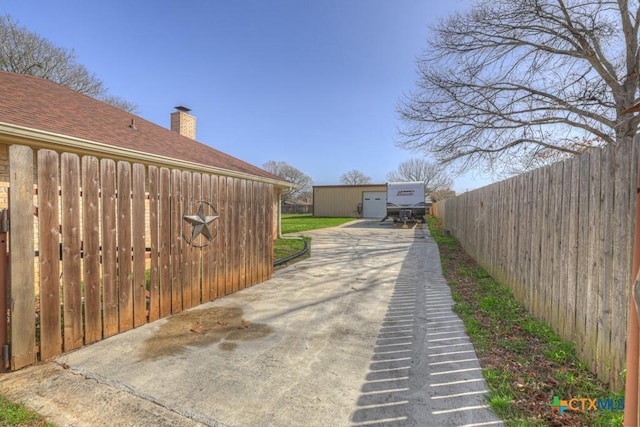 exterior space with a shingled roof, fence, and an outdoor structure