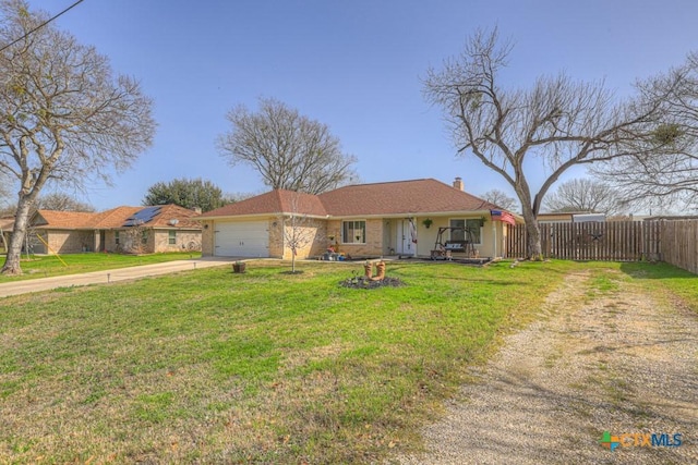 ranch-style home with an attached garage, fence, concrete driveway, a chimney, and a front yard