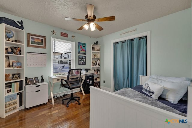 bedroom with ceiling fan, a textured ceiling, and wood finished floors