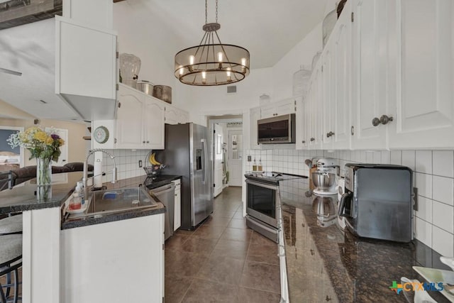 kitchen with dark countertops, appliances with stainless steel finishes, white cabinets, and a sink