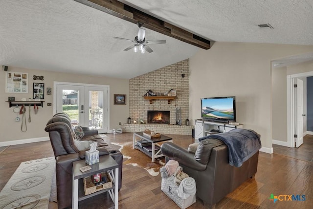 living area featuring french doors, lofted ceiling with beams, a brick fireplace, a textured ceiling, and wood finished floors