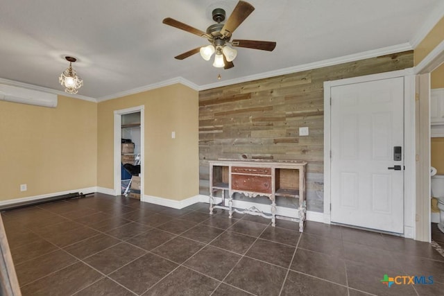 unfurnished living room with wooden walls, baseboards, ceiling fan, ornamental molding, and dark tile patterned floors