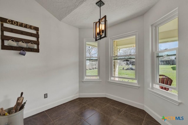 unfurnished dining area with a textured ceiling, baseboards, and a wealth of natural light