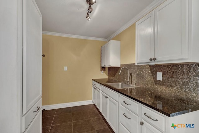 kitchen with crown molding, a sink, dark tile patterned floors, and decorative backsplash