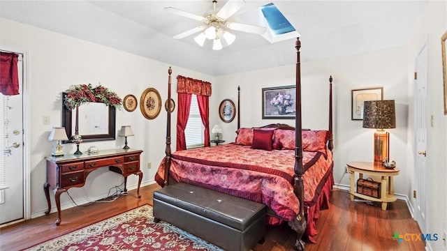 bedroom featuring a skylight, wood finished floors, baseboards, and ceiling fan