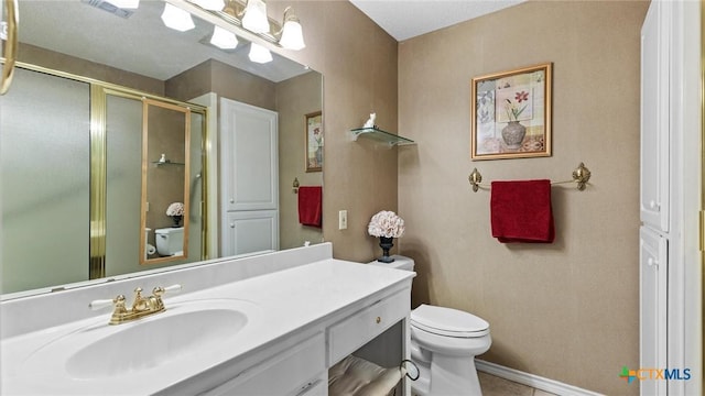 bathroom with visible vents, toilet, a stall shower, baseboards, and vanity