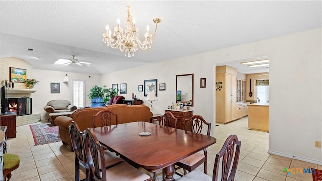 dining space featuring light tile patterned floors, plenty of natural light, a lit fireplace, and ceiling fan